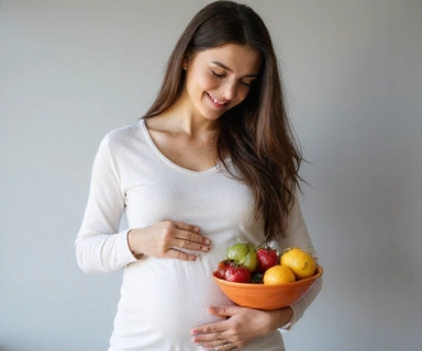 Una mujer embarazada sonriendo y acariciando su vientre, sosteniendo un tazón de frutas frescas.